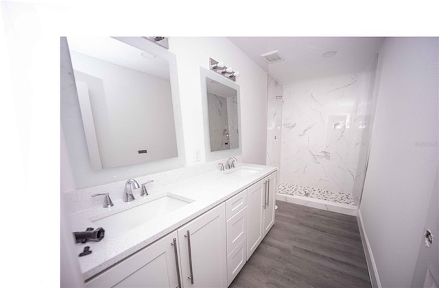 bathroom featuring hardwood / wood-style floors, vanity, and a tile shower