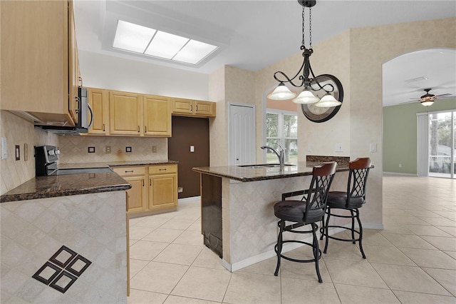 kitchen featuring stove, ceiling fan with notable chandelier, sink, light tile patterned floors, and hanging light fixtures