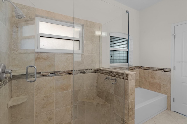 bathroom featuring tile patterned flooring, plus walk in shower, and tile walls