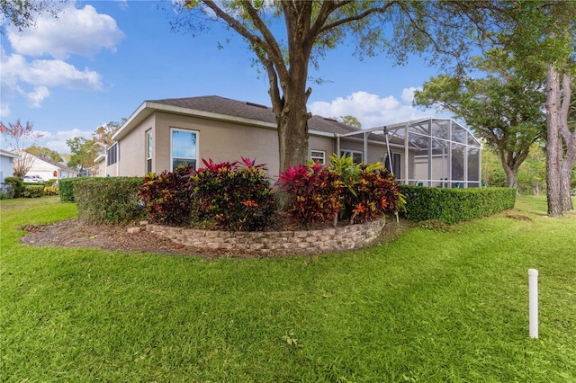 rear view of property featuring a yard and glass enclosure