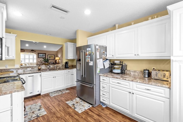 kitchen featuring a textured ceiling, hardwood / wood-style flooring, stainless steel appliances, and white cabinetry