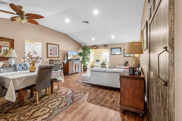 living room with hardwood / wood-style flooring, a textured ceiling, ceiling fan, and vaulted ceiling