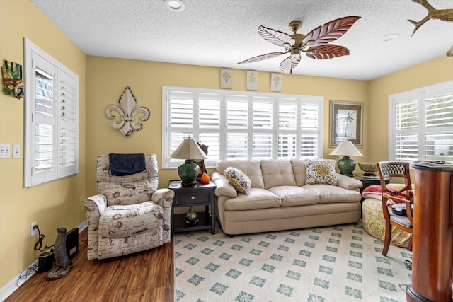 living room featuring ceiling fan, a textured ceiling, and hardwood / wood-style flooring