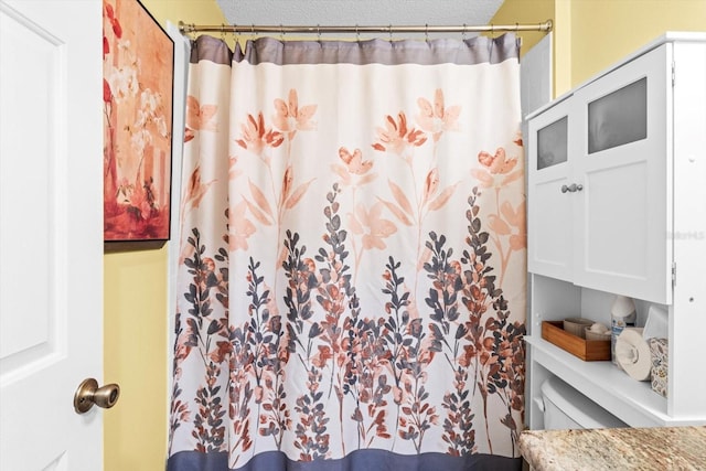 bathroom featuring a textured ceiling, toilet, and walk in shower