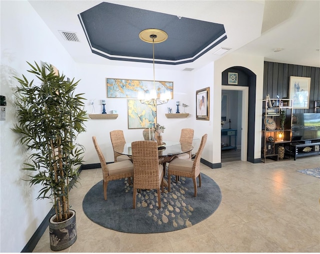 dining space featuring a chandelier, tile patterned flooring, and a raised ceiling