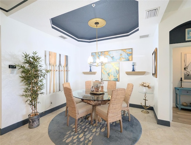 dining area featuring a chandelier, light tile patterned floors, and a tray ceiling