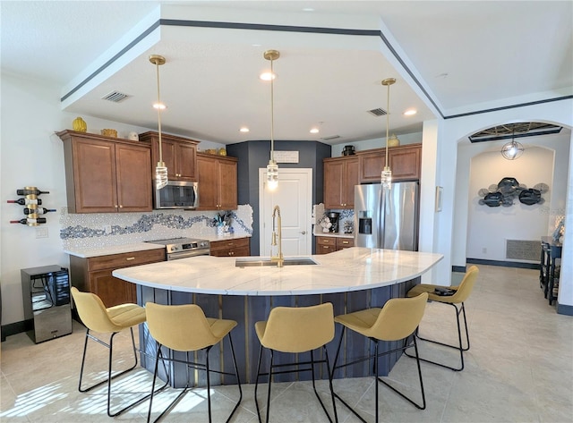 kitchen featuring decorative backsplash, stainless steel appliances, a spacious island, sink, and pendant lighting