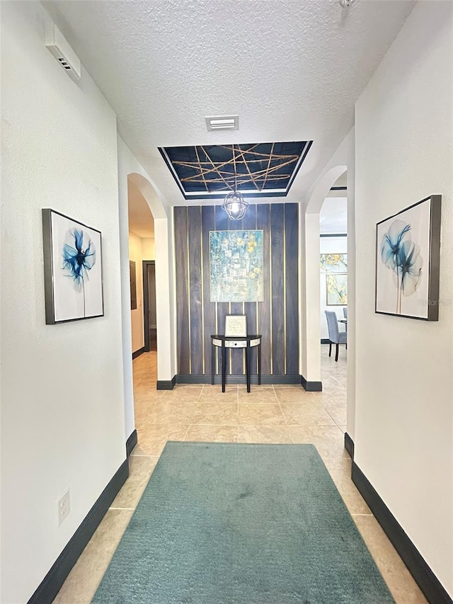 corridor featuring visible vents, arched walkways, and a textured ceiling