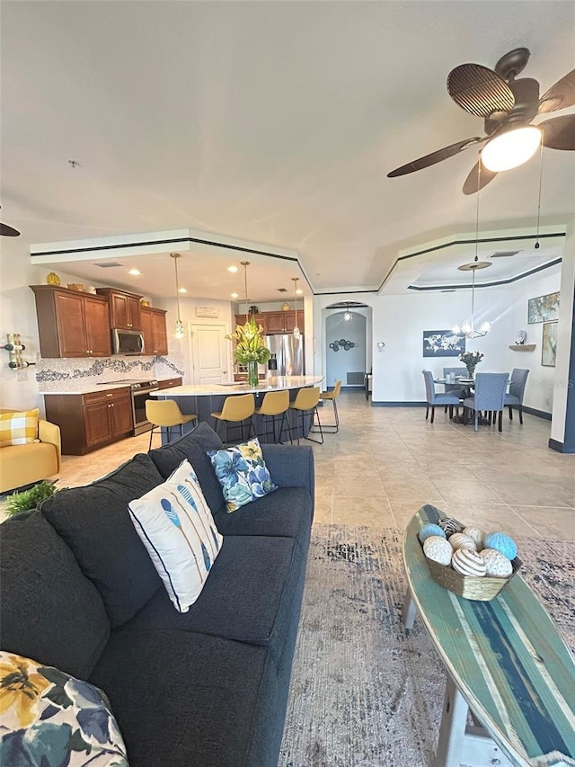 living room featuring baseboards, light tile patterned floors, and ceiling fan