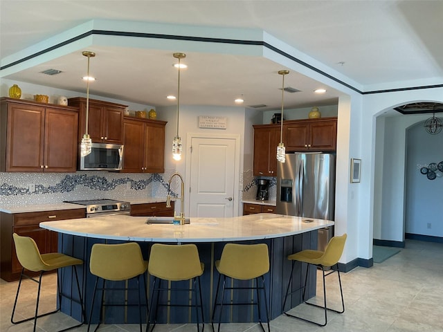 kitchen with a sink, stainless steel appliances, tasteful backsplash, visible vents, and arched walkways
