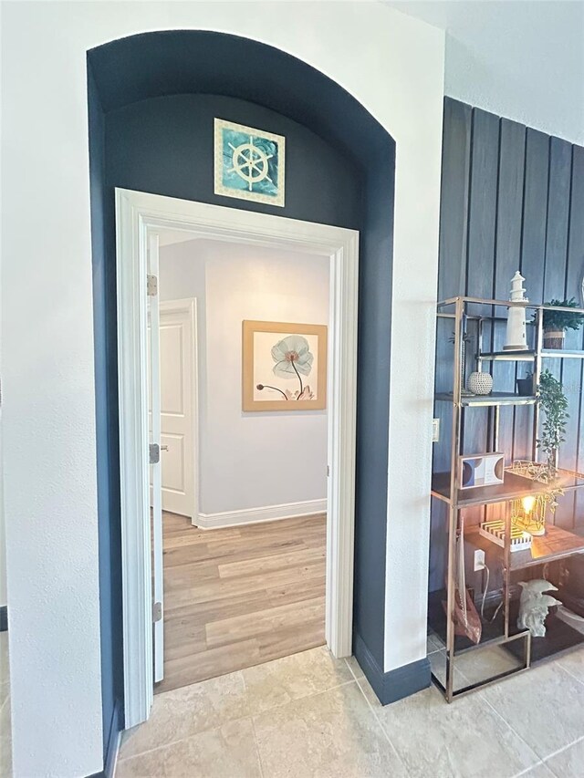 hall featuring baseboards and arched walkways