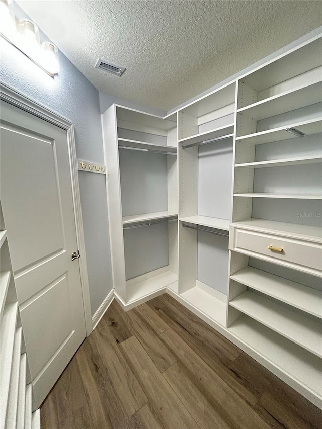 spacious closet featuring dark wood-type flooring and visible vents