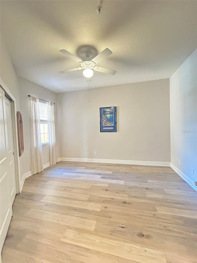 spare room featuring ceiling fan, light wood-type flooring, and baseboards