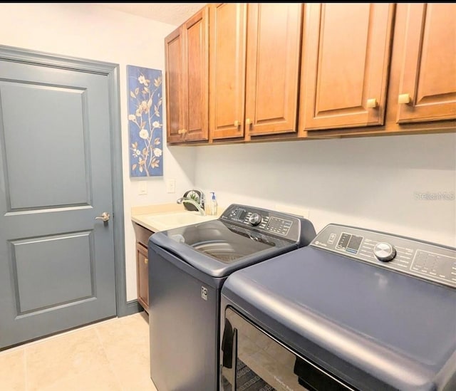laundry room with tile patterned floors, washer and dryer, cabinet space, and a sink