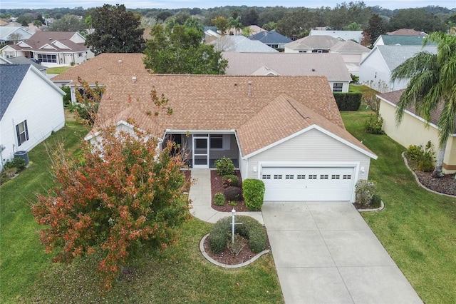 view of front of property featuring a shingled roof, an attached garage, a front yard, a residential view, and driveway