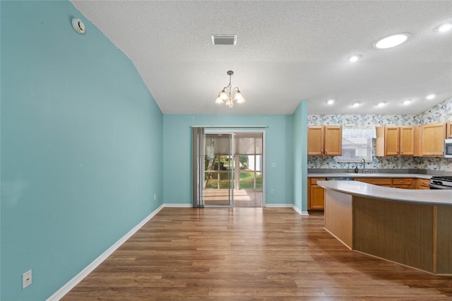 kitchen featuring a textured ceiling, a notable chandelier, wood finished floors, and baseboards