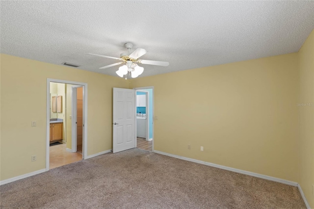 unfurnished bedroom featuring light colored carpet, visible vents, connected bathroom, a textured ceiling, and baseboards