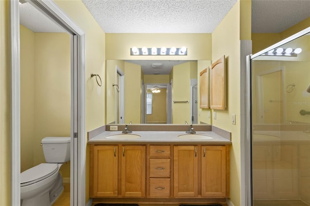 full bathroom featuring a stall shower, a sink, a textured ceiling, and toilet