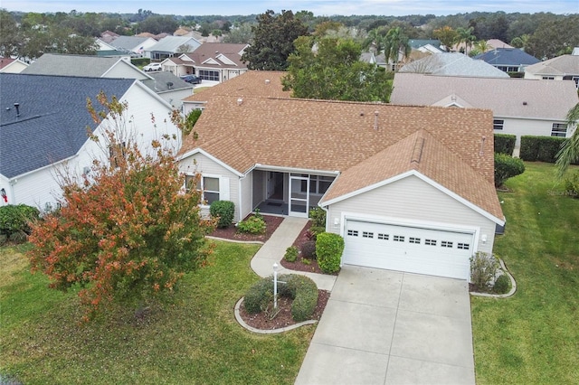 view of front of house with a shingled roof, concrete driveway, a front lawn, and an attached garage