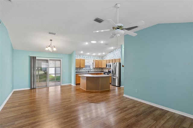 kitchen featuring appliances with stainless steel finishes, open floor plan, a kitchen island, vaulted ceiling, and wood finished floors