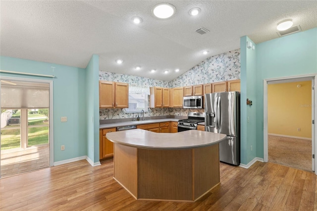 kitchen featuring lofted ceiling, appliances with stainless steel finishes, light wood-style flooring, and visible vents