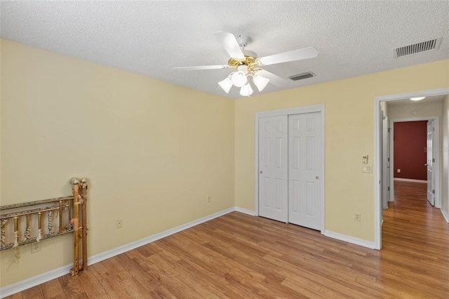 unfurnished bedroom featuring light wood-style floors, baseboards, visible vents, and a textured ceiling