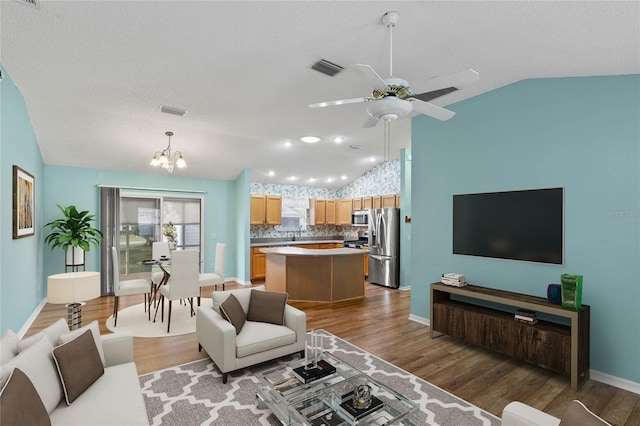 17848 SE 87th Bourne Ave, The Villages, FL 32162 - living room with vaulted ceiling, a chandelier, light wood-type flooring, ceiling fan, and a textured ceiling