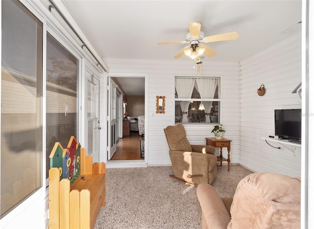 living room with ceiling fan and wooden walls