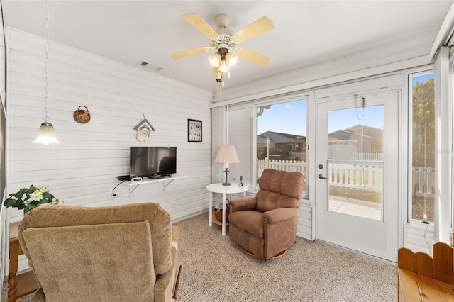 living room featuring ceiling fan and wooden walls