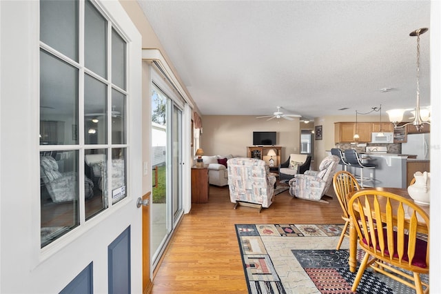 living room with ceiling fan, light hardwood / wood-style floors, and a textured ceiling