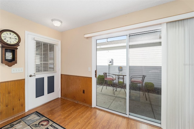 doorway to outside featuring wood walls, hardwood / wood-style floors, and a textured ceiling