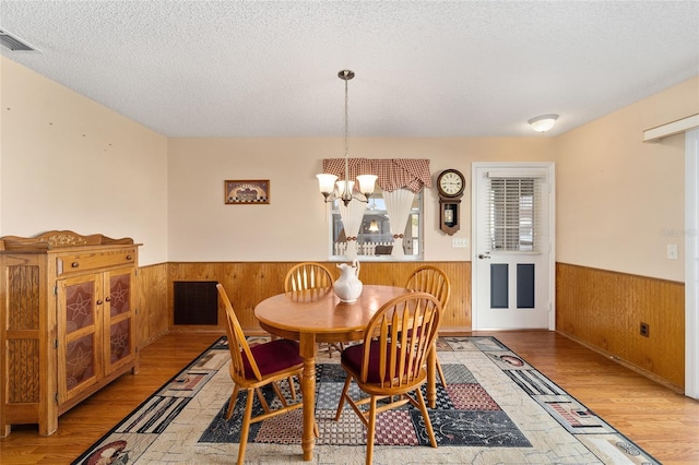 dining room with a textured ceiling, a chandelier, and light wood-type flooring