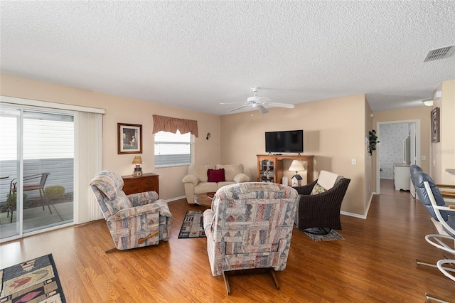 living room featuring a textured ceiling, ceiling fan, and light hardwood / wood-style flooring