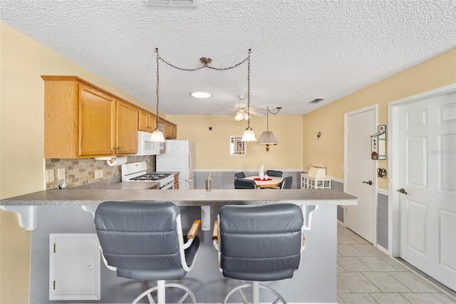 kitchen featuring white appliances, kitchen peninsula, a kitchen breakfast bar, and decorative backsplash