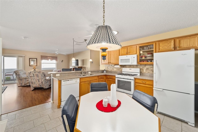 kitchen with white appliances, hanging light fixtures, kitchen peninsula, sink, and light tile patterned flooring