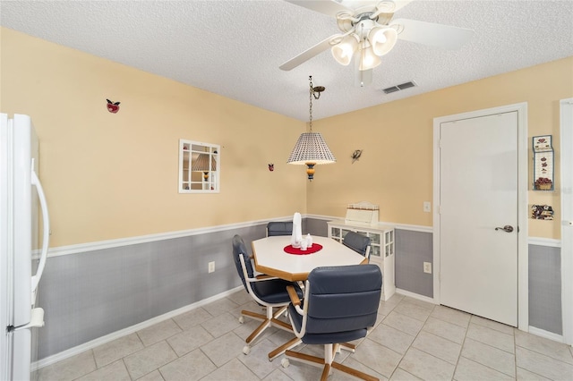 dining area with a textured ceiling, ceiling fan, and light tile patterned floors