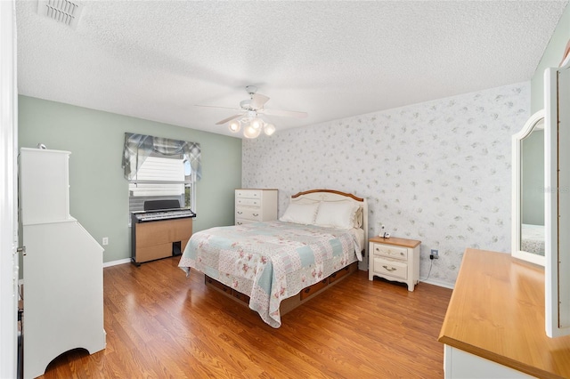 bedroom featuring light wood-type flooring, ceiling fan, and a textured ceiling