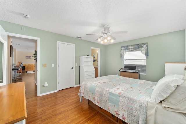 bedroom featuring ceiling fan, light wood-type flooring, and a textured ceiling