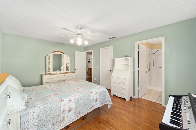 bedroom with connected bathroom, a textured ceiling, ceiling fan, and light wood-type flooring