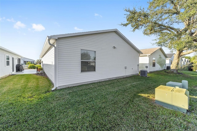 view of side of property with central AC unit and a lawn