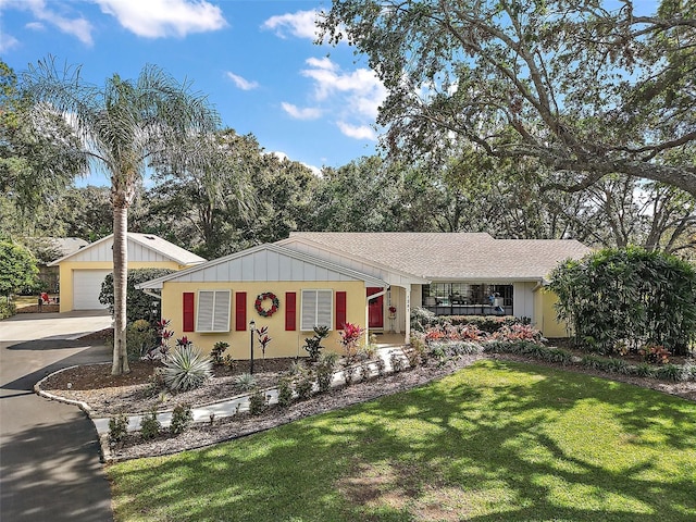 ranch-style home with an outdoor structure, a front lawn, a porch, and a garage