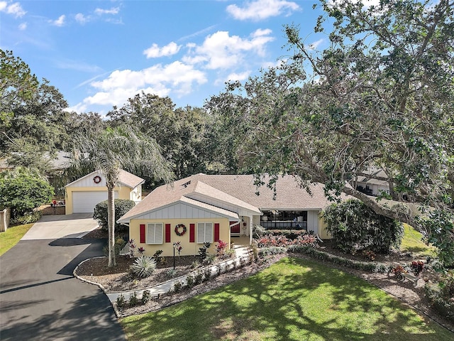 ranch-style house with a porch, a garage, a front lawn, and an outdoor structure