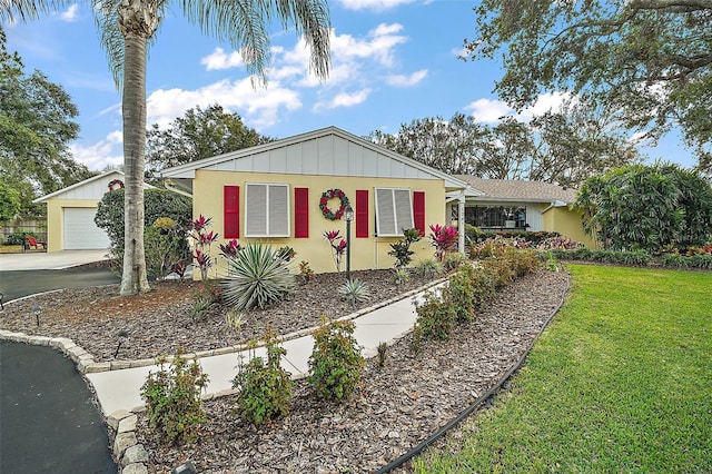 single story home with a front yard, a garage, and an outdoor structure