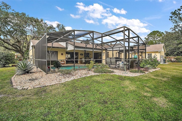 rear view of house featuring a lawn, glass enclosure, and ceiling fan