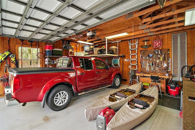 garage featuring a workshop area, wood walls, and a garage door opener