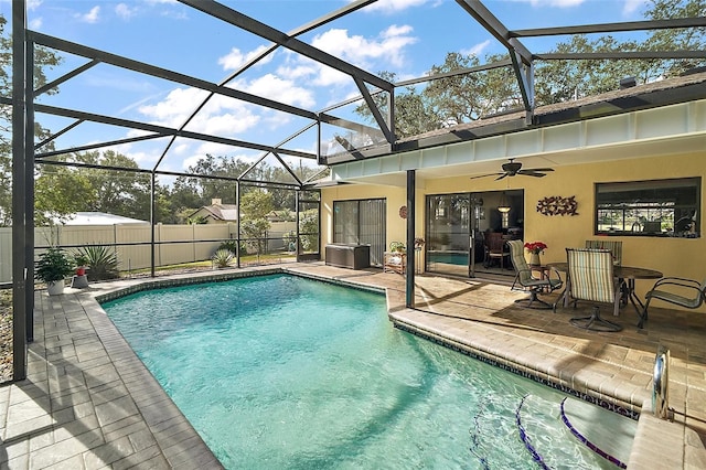 view of swimming pool featuring a patio area, ceiling fan, and glass enclosure