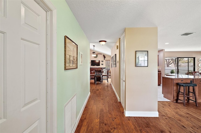 hallway with dark hardwood / wood-style flooring, lofted ceiling, and a textured ceiling