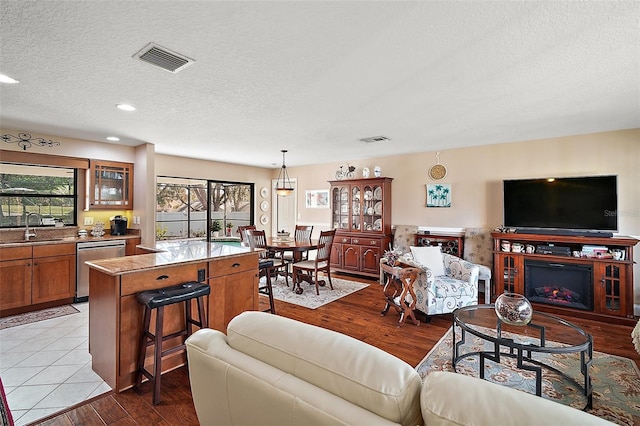 living room with a textured ceiling, light hardwood / wood-style floors, and sink