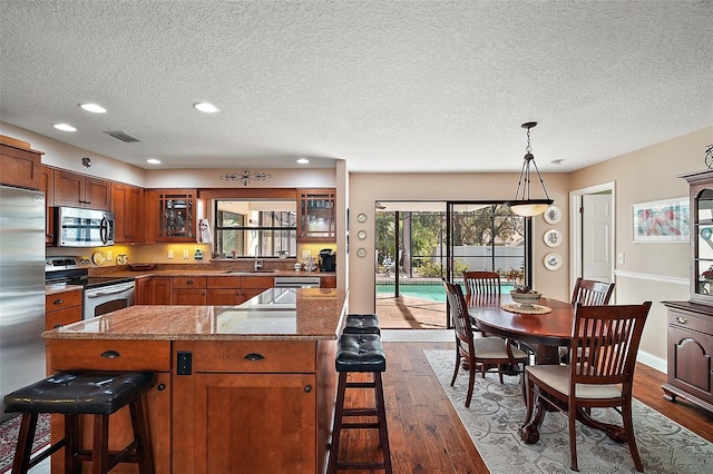 kitchen featuring pendant lighting, sink, appliances with stainless steel finishes, and a breakfast bar area