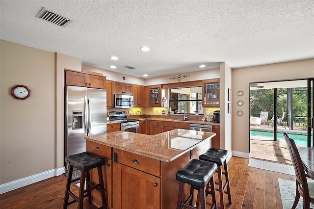 kitchen with dark hardwood / wood-style flooring, light stone countertops, a breakfast bar, and stainless steel appliances